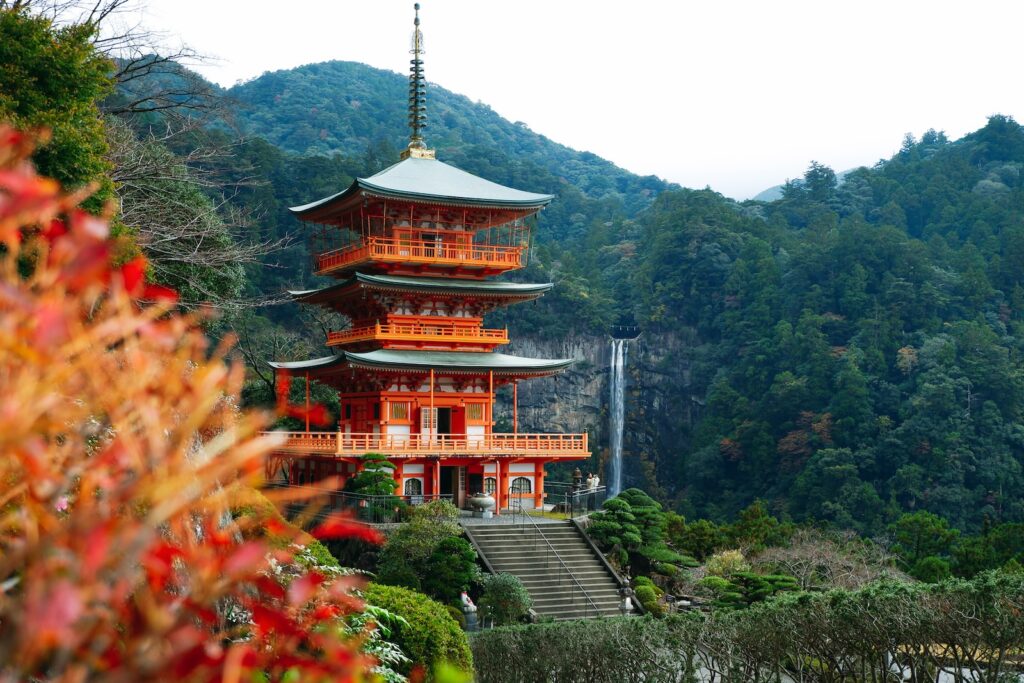brown and white temple surrounded by green trees during daytime. Nachi Falls Wakayama